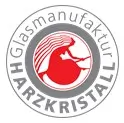 Logo der Glasmanufaktur Harzkristall. Unser Partner unter dem Dach der Gerhard Bürger Stiftung. Zentral ist eine rote Brockenhexe zu sehen. Umgeben von einem grauen Kreis sowie der Firmierung.