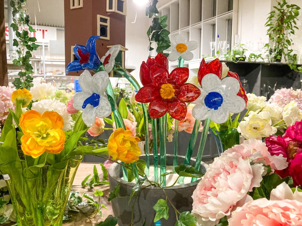 Glasblumen arraangiert mit weiteren Kunstblumen zu einem immergünen Strauß