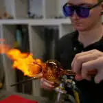 Glasbläser in der ELIAS Glashütte Lauscha treibt den Boden einer Vase auf an der Lampe, dem Brenner, auf