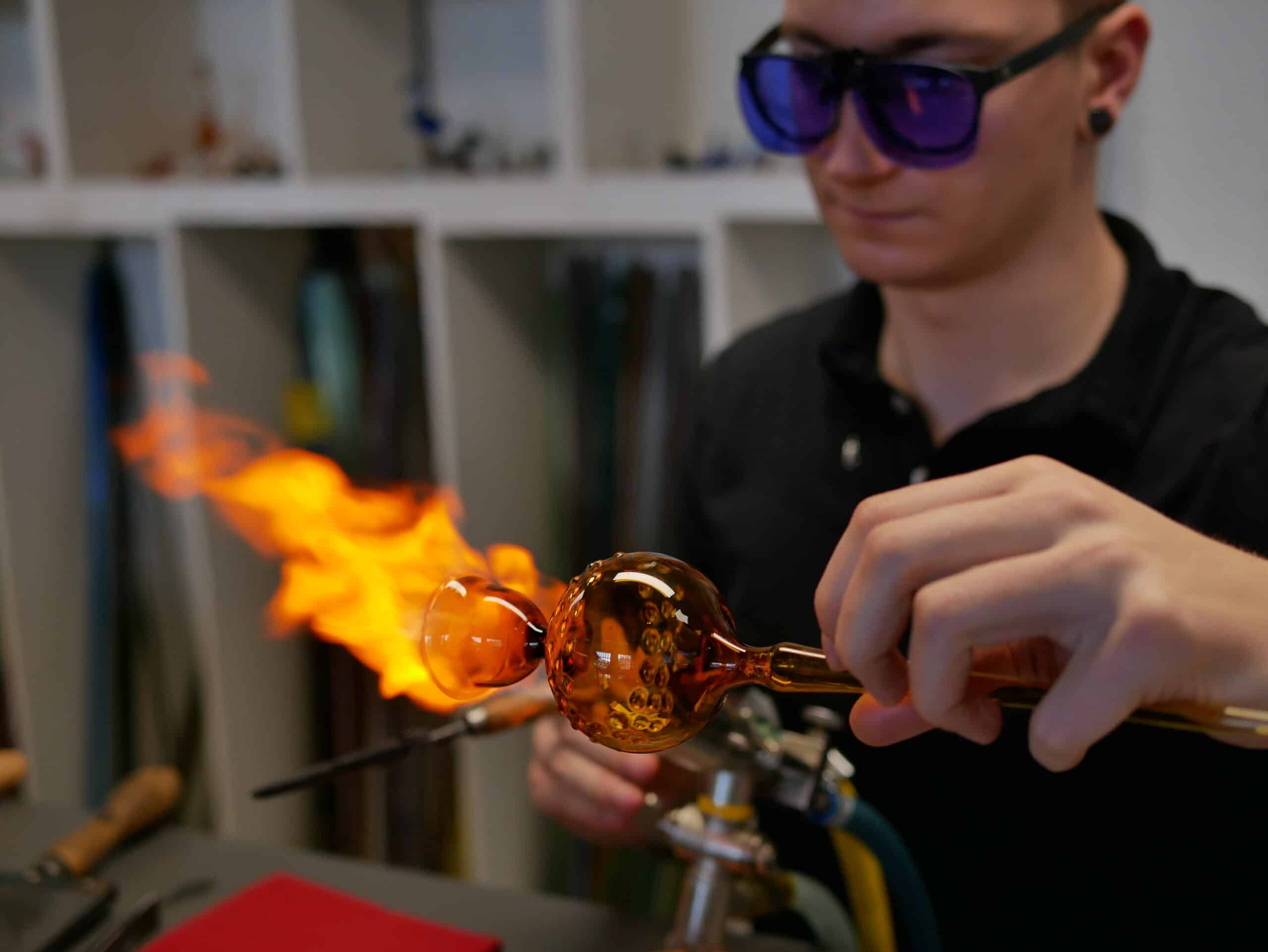Glasbläser in der ELIAS Glashütte Lauscha treibt den Boden einer Vase auf an der Lampe, dem Brenner, auf