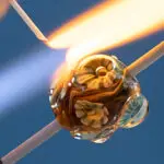 Wickeln einer Glasperle mit Glastäben am Brenner. Aufsetzen einer Dekoration.